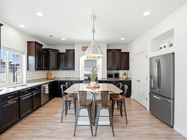 Bright kitchen with dark cabinets, stainless steel appliances, and an island with seating.