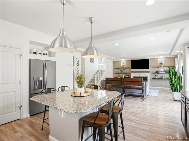 Open-plan kitchen with a granite island, stainless steel appliances, and pendant lights beside the living area.