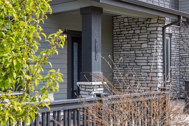 Home exterior with a covered porch, stone facade, and address 2018 on a pillar.