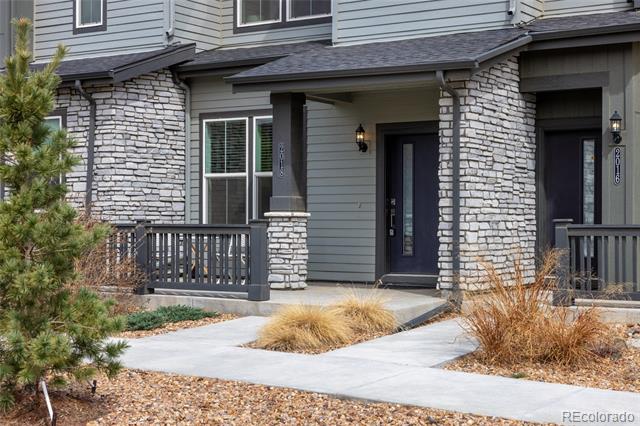 Gray-sided home with stone porch columns, dark entry doors, and a landscaped front walkway.