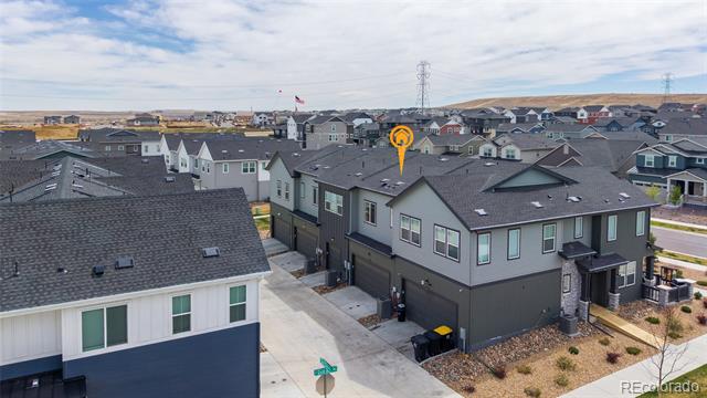 Aerial view of a gray multi-unit home with attached garages and neighboring residences.