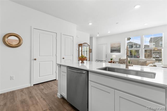 Bright kitchen with a large white island, undermount sink, and stainless steel dishwasher.