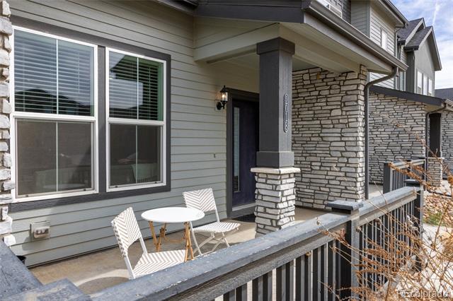Covered porch with stone columns, gray siding, and a white patio table and chairs.