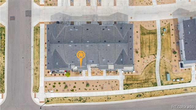 Aerial view of a gray-roofed residential building at a street corner, marked with an orange location pin.