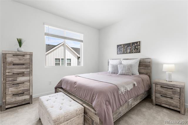 Furnished bedroom with mauve bedding, a wood bed frame, and a tufted storage bench.