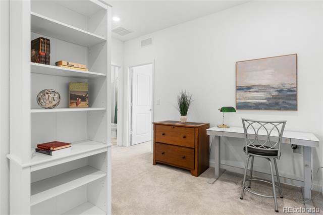 Home office with built-in shelving, a wooden chest of drawers, and a desk beneath abstract artwork.