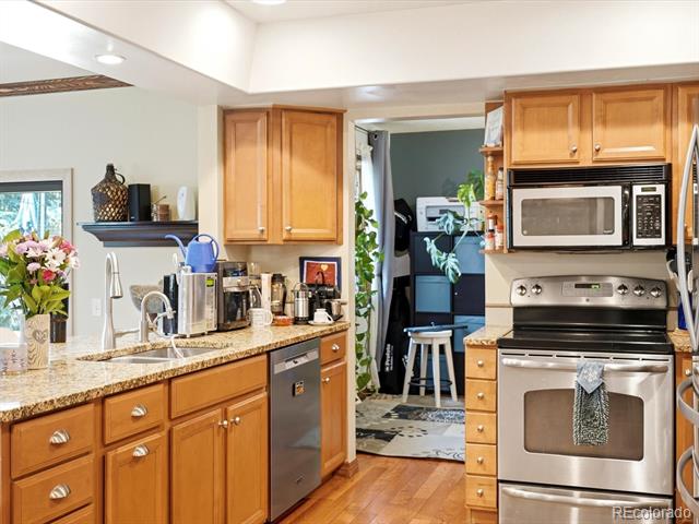 Kitchen with honey-colored cabinets, granite countertops, and stainless steel appliances.