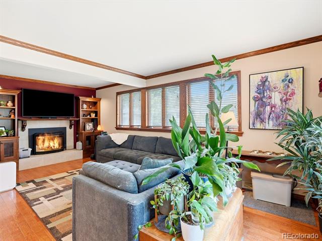 Living room with a gray sectional, lit fireplace, built-in shelving, and large windows.