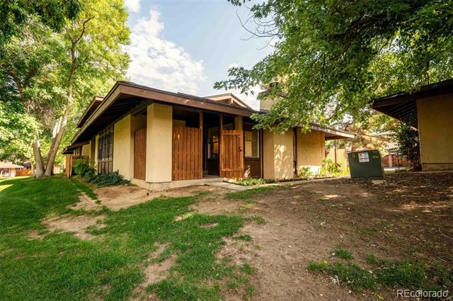 Single-story home with broad roof eaves, a wood-paneled entry, and mature trees in the front yard.