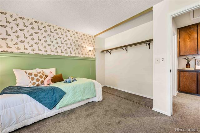 Bedroom with a green paneled wall, bird-patterned wallpaper, and an open closet.