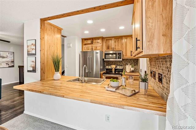 Kitchen with light wood cabinets, stainless steel appliances, and a broad butcher-block peninsula.