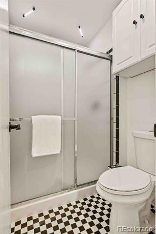 Bathroom with a frosted-glass shower and black-and-white checkerboard floor.
