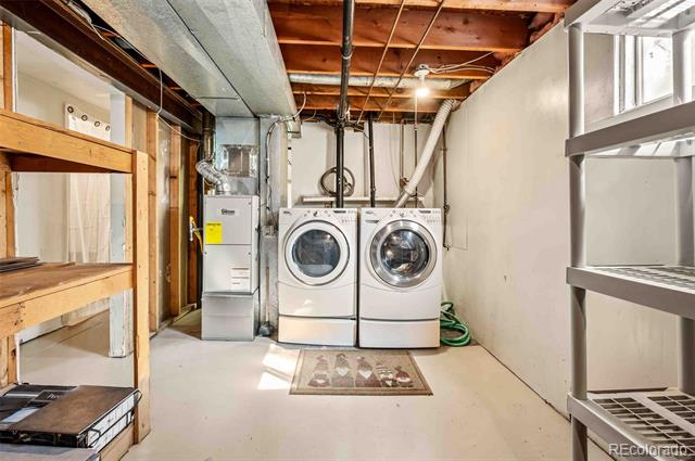 Basement laundry area with front-loading washer and dryer and exposed ceiling joists.