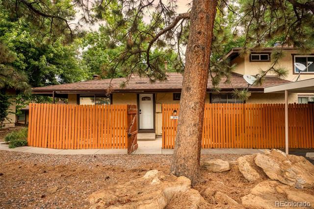 Home behind orange slat fencing, partly screened by a large pine tree.