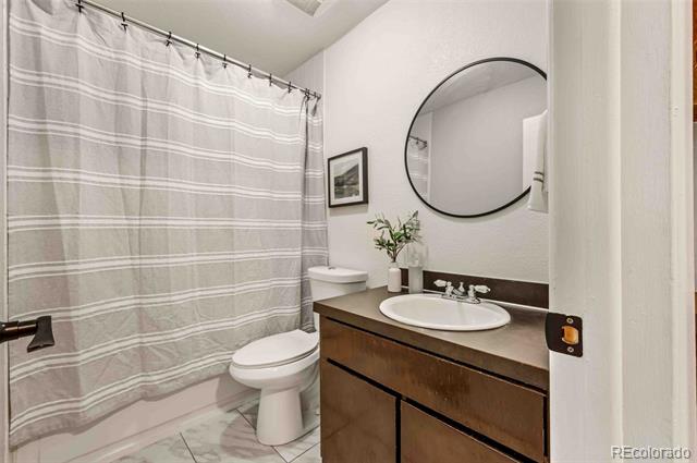Bathroom with a gray striped shower curtain, dark wood vanity, and large round mirror.