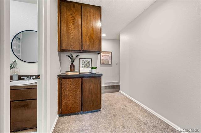 Hallway with a large built-in wood cabinet and a bathroom vanity visible through the doorway.