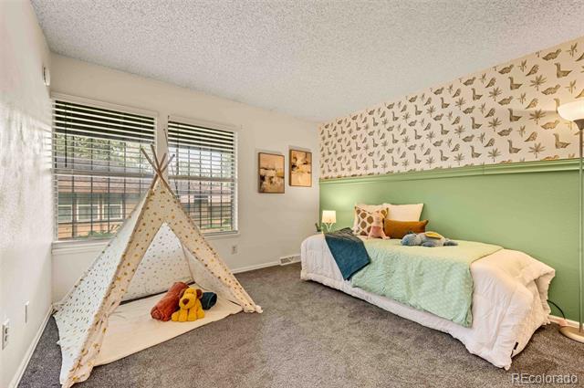 Bedroom with a mint-green accent wall, bird-patterned wallpaper, and a fabric teepee beside the windows.
