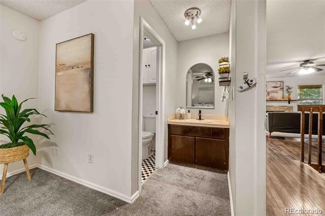 Bathroom vanity with dark wood cabinetry and an arched mirror beside an adjoining toilet nook.