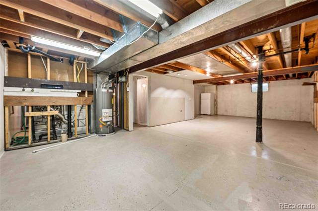 Unfinished basement with a broad concrete floor, exposed beams, and visible utility equipment.