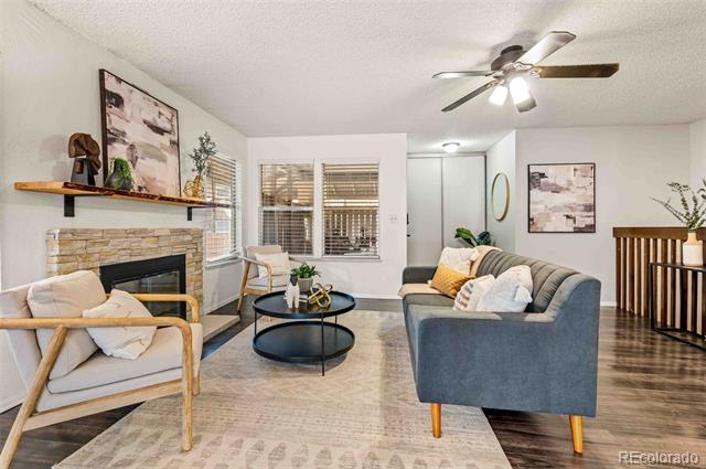 Living room with a gray sofa, fireplace, round coffee table, and staircase railing.