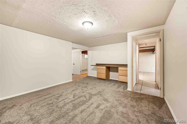 Carpeted room with a built-in desk and doorways to adjoining rooms.