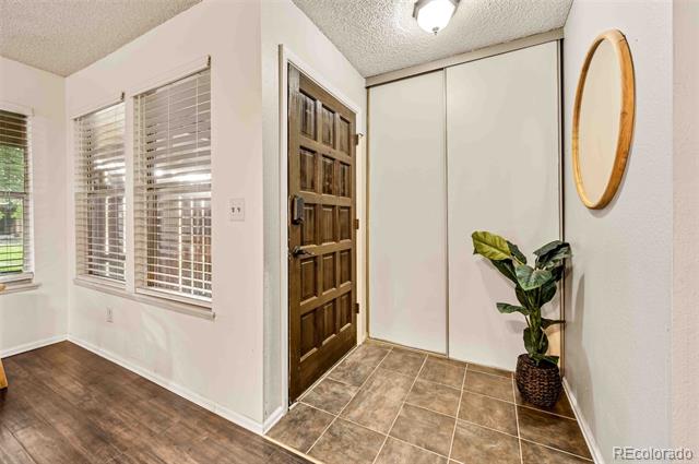 Entryway with a dark paneled front door, tiled floor, round mirror, and potted plant.