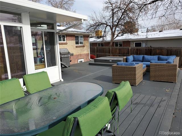 Raised deck with green dining chairs, blue lounge seating, and a hot tub.