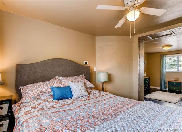 Bedroom with patterned bedding, a dark upholstered headboard, and an open doorway to an adjoining room.