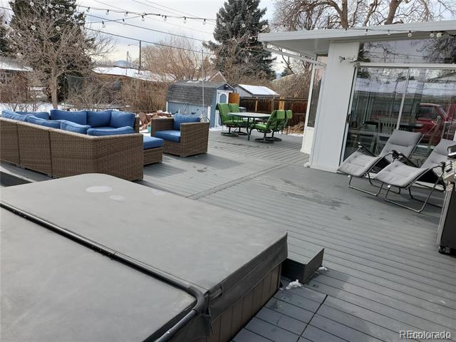 Deck with covered hot tub, blue-cushioned seating, dining set, and lounge chairs.