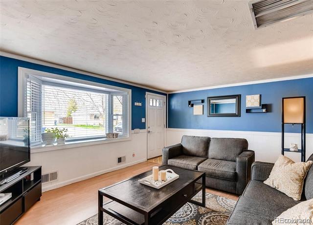 Living room with blue walls, a gray sectional sofa, and a large window with blinds.
