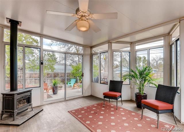 Sunroom with expansive windows, a wood-burning stove, and two chairs facing a fenced backyard.
