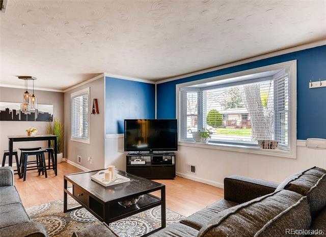 Living room with a large bay window, blue accent wall, and adjoining dining area.