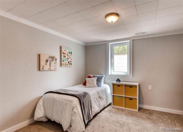 Bedroom with a single bed, framed wall art, and colorful cube storage beneath the window.