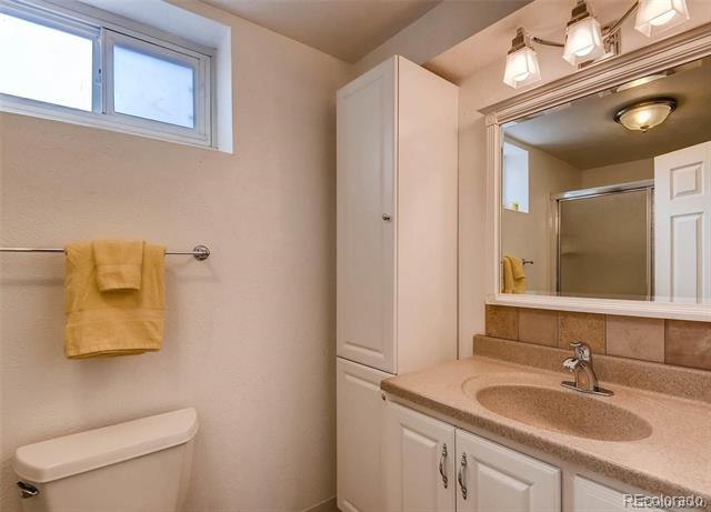 Bathroom with a white vanity, large mirror, and mustard-yellow towel.