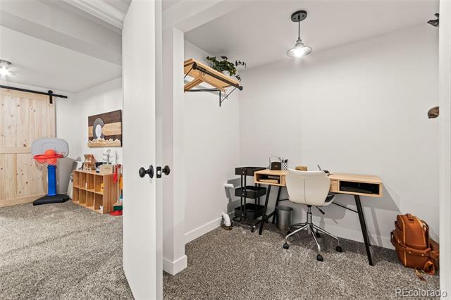 Home office with a desk and rolling chair beside a play area with a small basketball hoop.