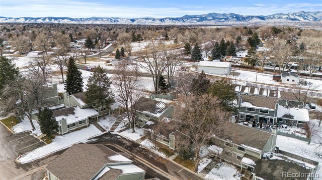 Aerial view of snow-covered homes with the Rocky Mountains in the distance.