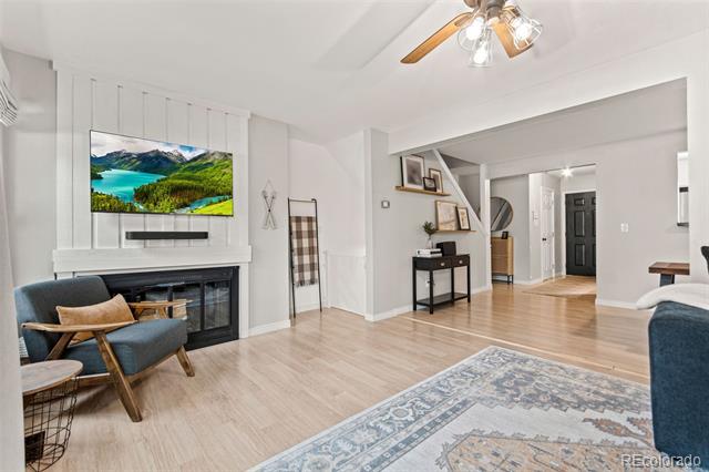 Furnished living room with a fireplace, wall-mounted television, and open entry hall.