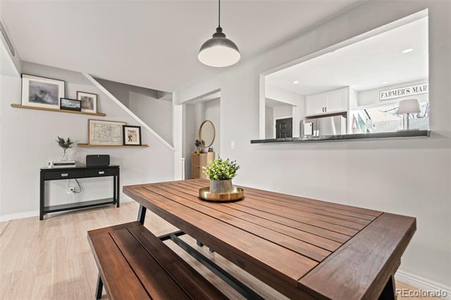Dining area with a long wooden table and benches, floating shelves, and a pass-through to the kitchen.