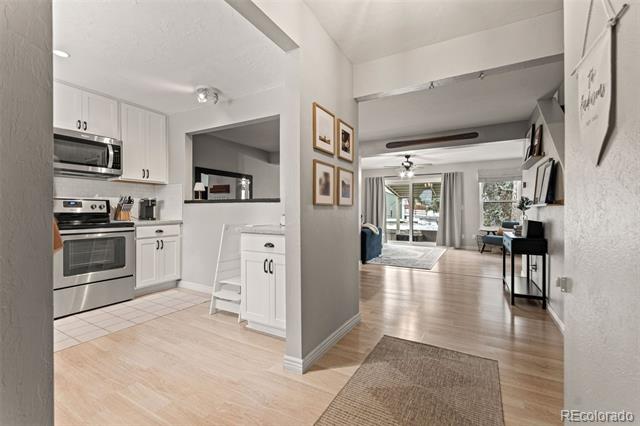 Open-concept kitchen and living area with stainless steel appliances, light wood floors, and balcony doors.