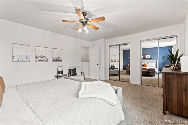 Bedroom with white bedding, mirrored closet doors, and a view into an adjoining blue room.