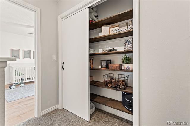 Closet with built-in dark shelves, baskets, framed photos, and a partly open white sliding door.