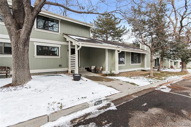 Pale green multi-unit building with covered patios and snow-covered lawn beside the street.