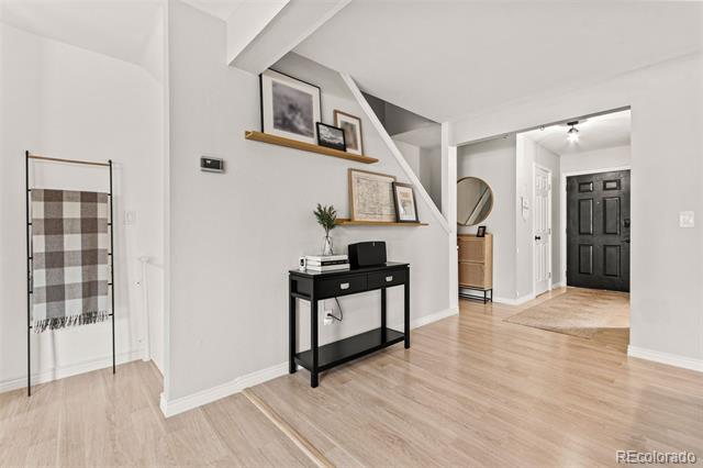 Entryway with light wood floors, a black console table, and floating display shelves.
