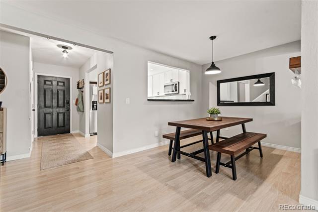 Dining area with a dark wood table and benches, light wood floors, and a kitchen pass-through.