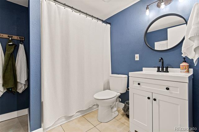 Bathroom with blue walls, white vanity, oval mirror, and shower curtain.