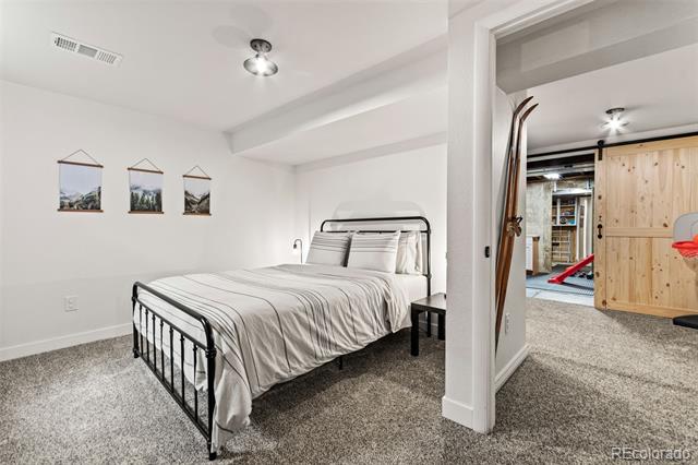 Bedroom with striped white bedding, a black metal bed frame, and an adjoining room visible through the doorway.