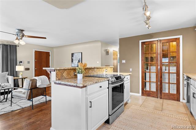 Open kitchen with a granite island, stainless steel appliances, and wood-framed glass French doors.