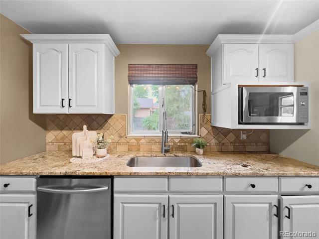 Kitchen with white cabinets, granite countertops, and a sink beneath a window.