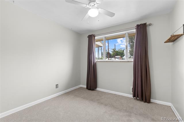 Unfurnished bedroom with a ceiling fan, carpet, and a curtained window.