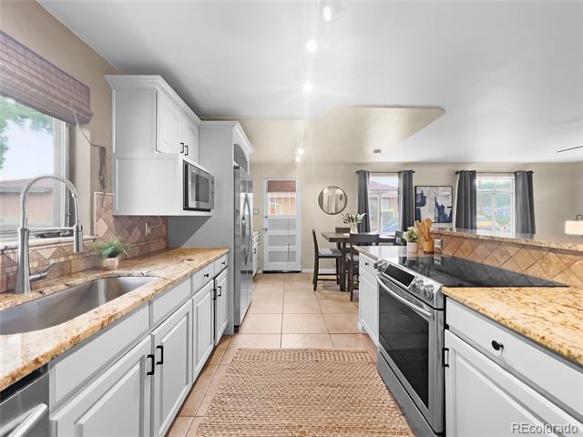 Bright kitchen with white cabinets, granite counters, stainless steel appliances, and a dining area.